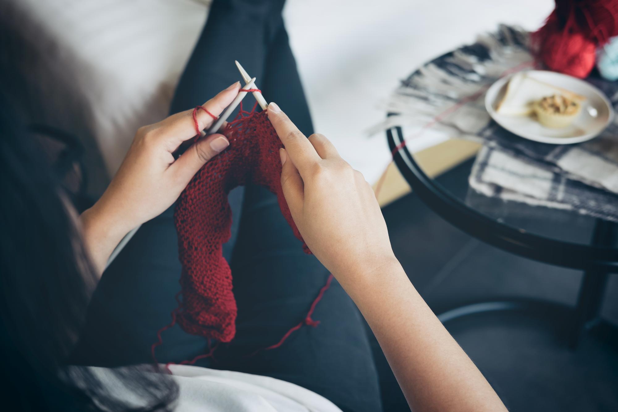 ręka układająca nici i igłę nad tkaniną